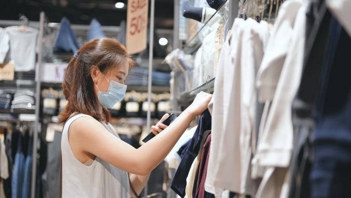 亚洲人面带微笑，戴着面具享受特价广告，在购物商场展示黑色星期五。重开后购物减价30-50%