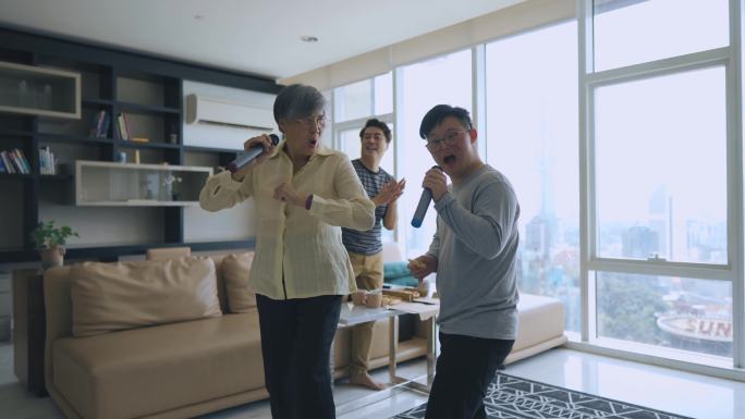 周末，多代亚裔中国男子在客厅与唐氏综合症儿子跳舞，与祖母唱歌跳舞，玩得很开心