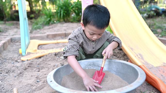 亚洲男孩在沙盒里玩沙子
