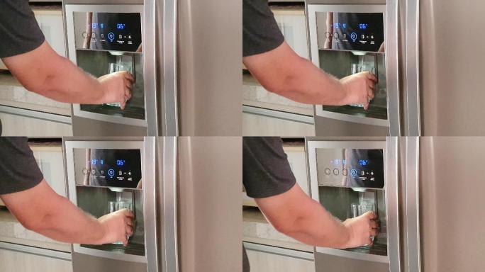 男子在冰箱饮水机前抓起一杯水。