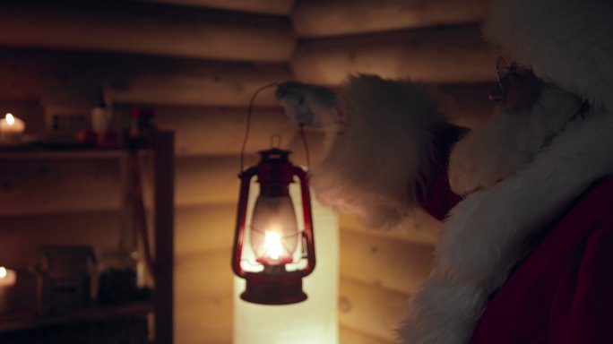 圣诞老人手里拿着一盏油灯，来到一座装饰精美的木屋前，屋里的灯由蜡烛点燃