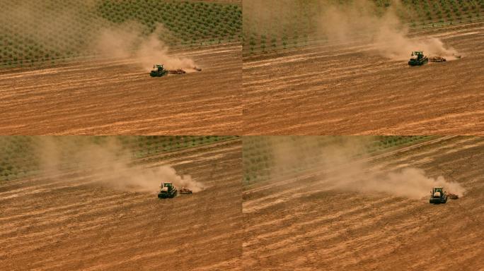 空中拖拉机在阳光下田间作业，拉着犁穿过田地