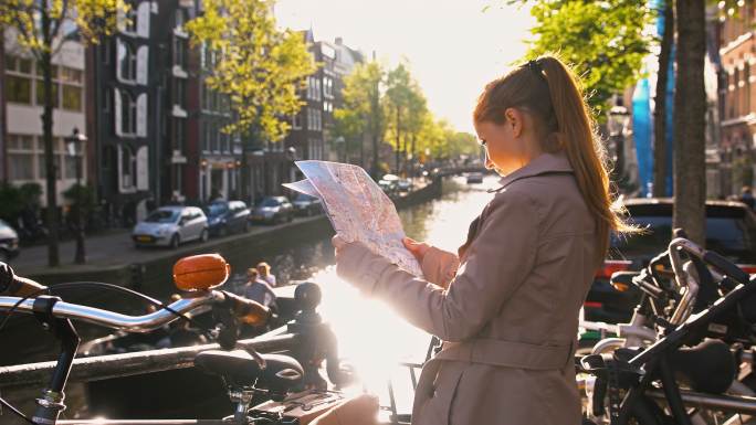 在阿姆斯特丹度假的女性游客，在一个阳光明媚的日子里，沿着运河散步，观光，看城市地图
