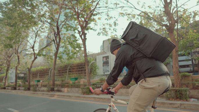 背着背包的送货员骑着自行车运送食物。