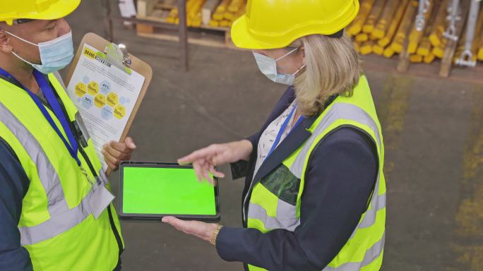 一对成年男女在仓库工作时使用绿色屏幕数字平板电脑的4k视频片段