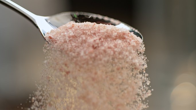 把粉红色的盐从勺子里倒出来