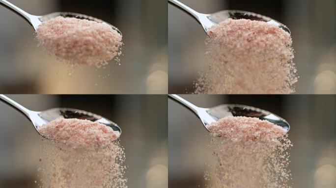 把粉红色的盐从勺子里倒出来