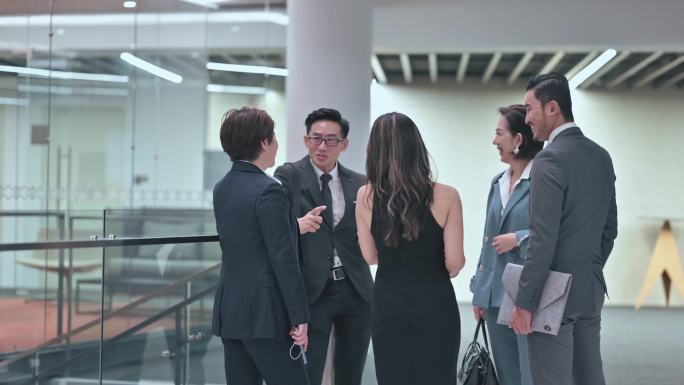 亚裔华裔商务装同事下班后在办公楼走廊交谈