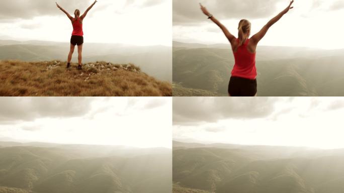 女子跑步者在山顶举手的空中技巧