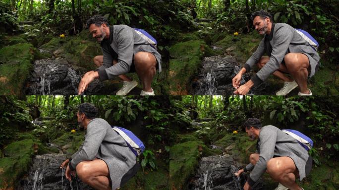 成熟的男人从森林里的溪流中提神喝水