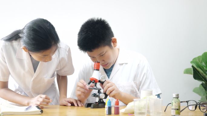 亚洲孩子在实验室里用显微镜进行科学实验，在家里的实验室里，教育他们的生活方式理念。