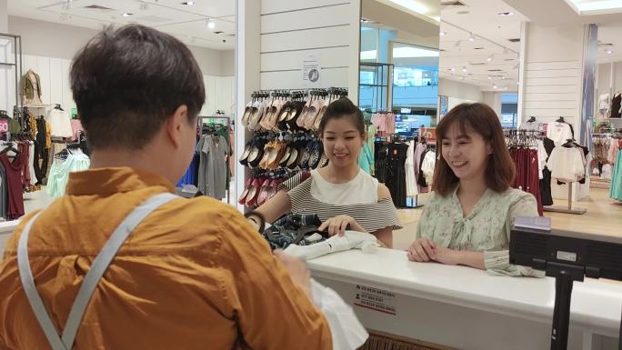 亚裔中国女性顾客走向收银台准备结账。