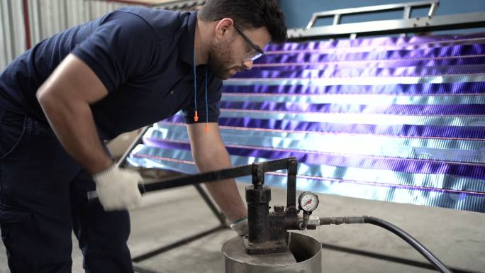 在太阳能电池板工厂，工人将水泵入电池板进行测试