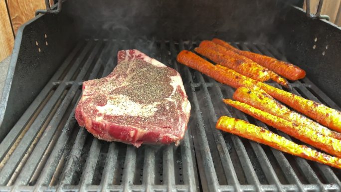 厚切生调味牛肉里贝耶牛排和有机胡萝卜，炭火烧烤4K视频