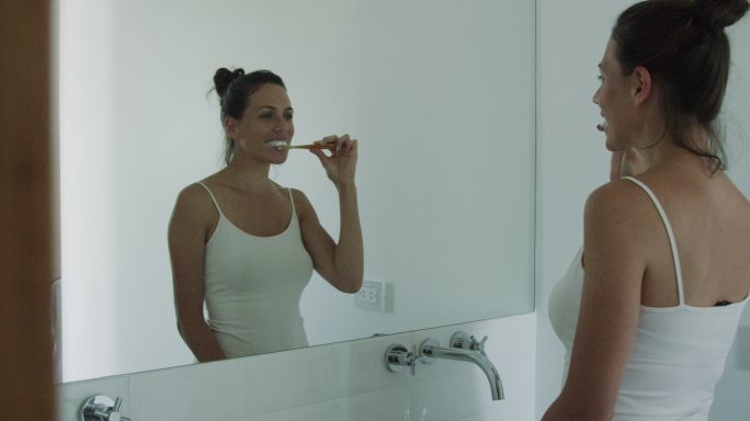 年轻女子一边刷牙一边看着镜子