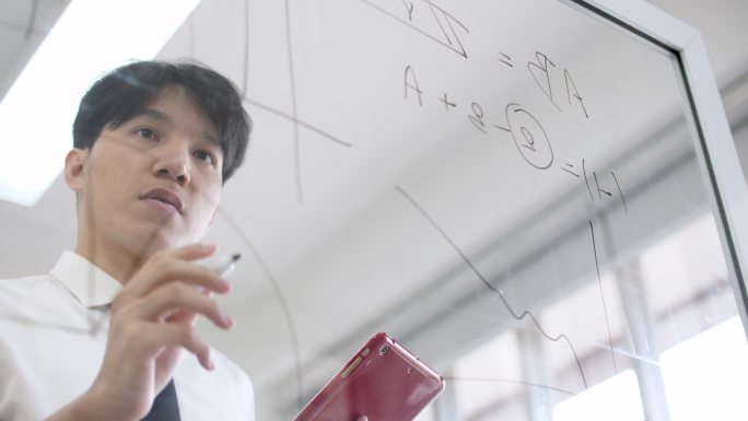商人在玻璃白板上写数学方程式，寻找解决方案和工作理念