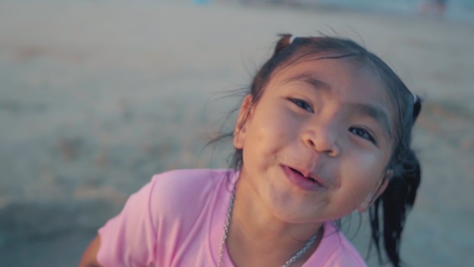 日落时分，小女孩在海滩上喜笑颜开。