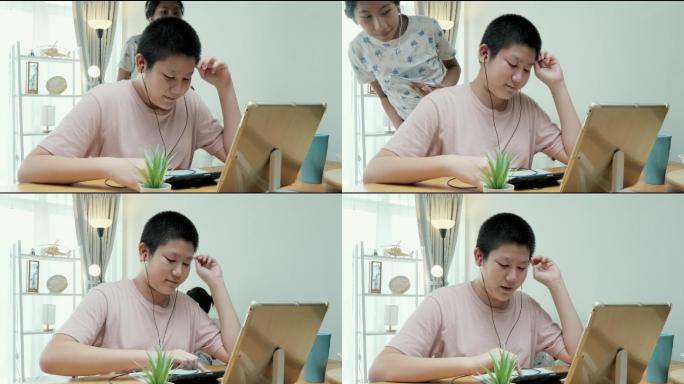 在2019冠状病毒疾病期间，一名亚洲女孩打断了她的弟弟，当时他正在家里餐桌上用数字平板电脑学习在线课
