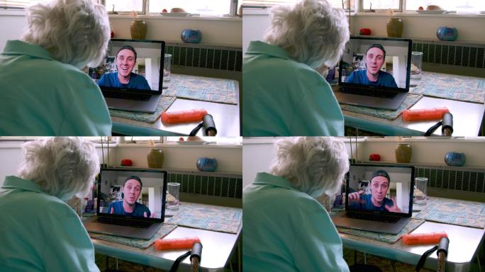 一位100岁的老太太坐在笔记本电脑前与孙子交谈并打视频电话