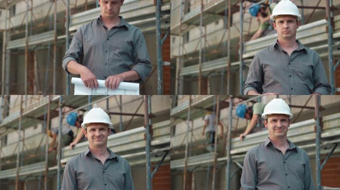 男建筑师戴着白色头盔，在施工现场滚动平面图，对着摄像机微笑