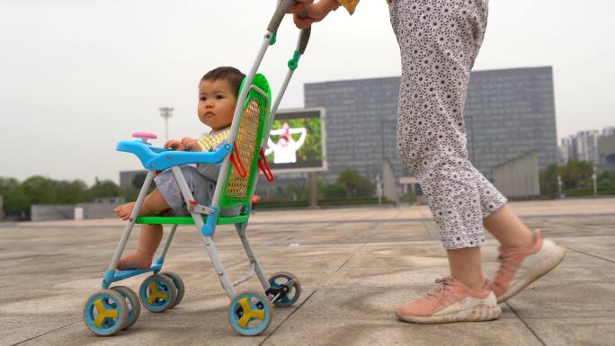 妈妈带小孩推婴儿车广场散步