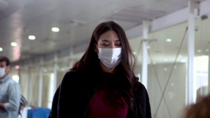 一名女子戴口罩，在机场将旅行证件交给值机代理