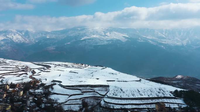 冬季阳光阴影白雪覆盖田野农村远处连绵雪山