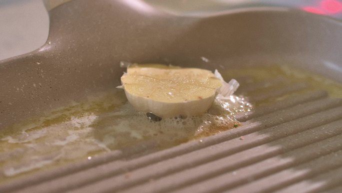 在烤盘里用融化的黄油烤半个蒜头的特写镜头