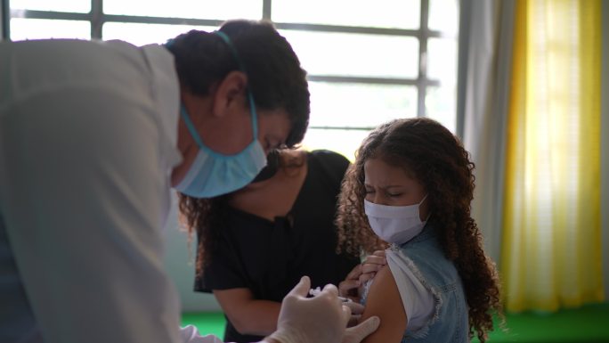 女童与母亲在接种中心接种疫苗