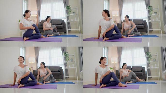 两位亚洲女性做半鱼王瑜伽姿势，右膝弯曲，右脚蜷缩在左臀附近，右臂在右耳旁笔直向上，然后将躯干向左扭转