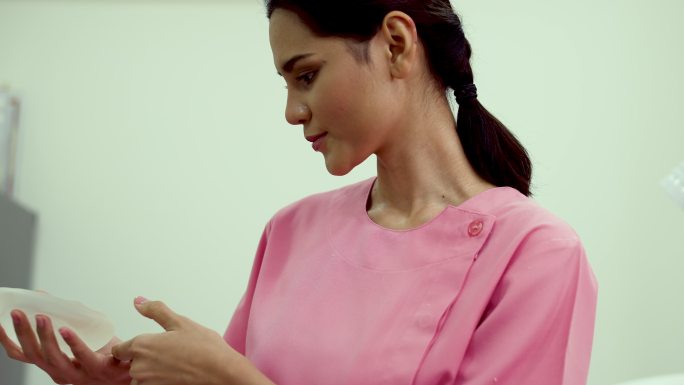 一名女性患者在诊所展示硅胶乳房植入物。