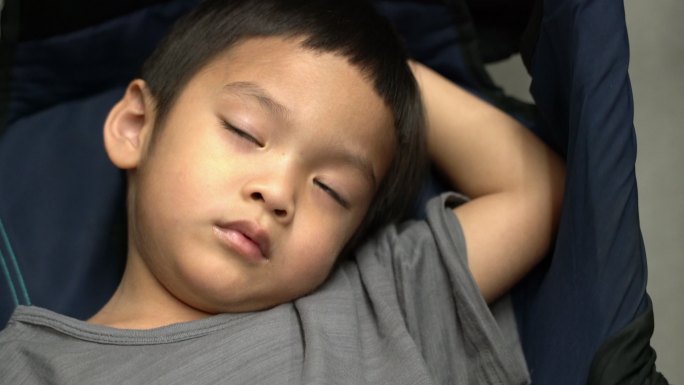 可爱疲惫的亚洲幼儿在旅行时在婴儿车上睡着了