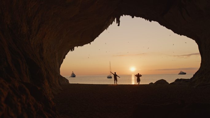 意大利撒丁岛卡拉卢纳，一对夫妇在海滩上跑步的慢镜头。