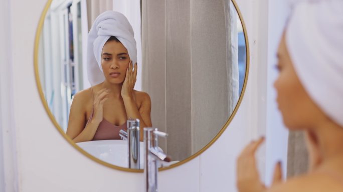 一个迷人的年轻女子在浴室镜子前检查自己脸的4k视频片段