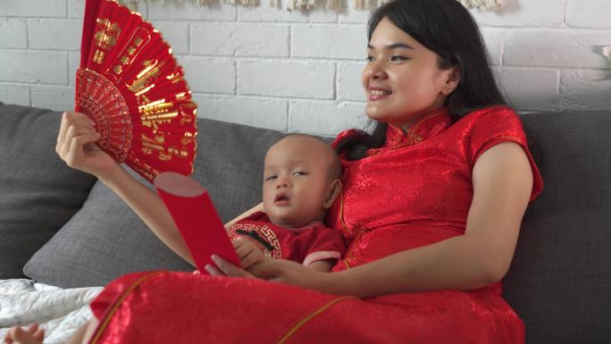 举着中国扇子的女子坐在家里参加imlek庆典
