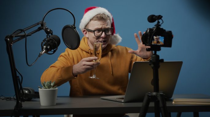 一位成功的流行博主用一杯香槟为自己的频道拍摄了一个圣诞节场景，并在节日期间高兴地向观众表示祝贺
