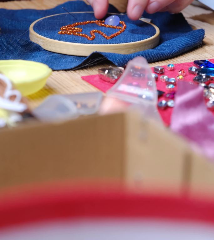 坐在书桌旁，在家里制作珠子和水晶首饰的成熟女性的双手