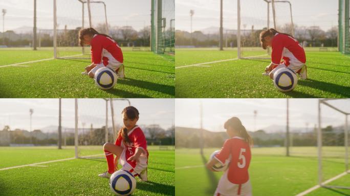 小学阶段的女性足球运动员或足球运动员，系上足球或足球鞋，然后拿着足球走进足球场