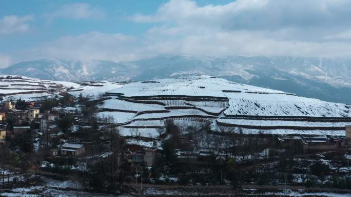 冬季阳光晴天白雪覆盖田野农村远处连绵雪山