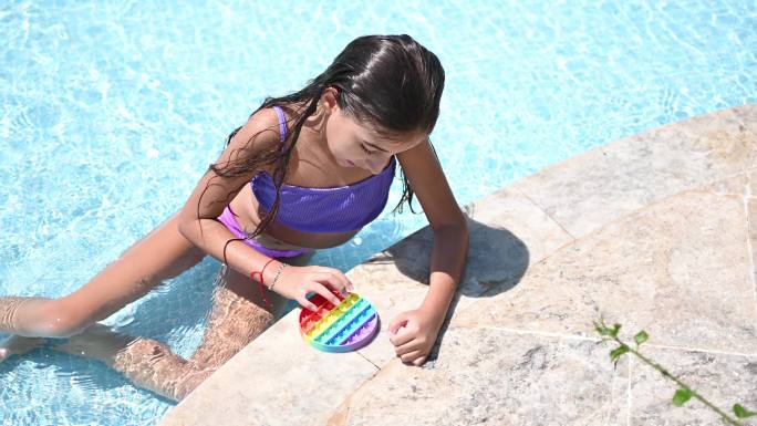 美丽的女孩在游泳池里享受着抗应激彩虹般的烦躁