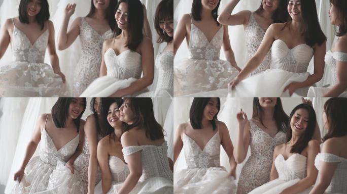 慢镜头快乐嬉戏的亚洲华人新娘和伴娘在婚纱店试穿婚纱，欢天喜地地共舞