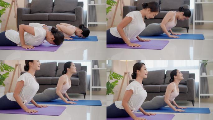 两位美丽的亚洲女性做鸽子瑜伽姿势和俯卧撑，通过伸展大腿和背部来帮助打开肩膀和胸部。伸向后方的腿得到伸