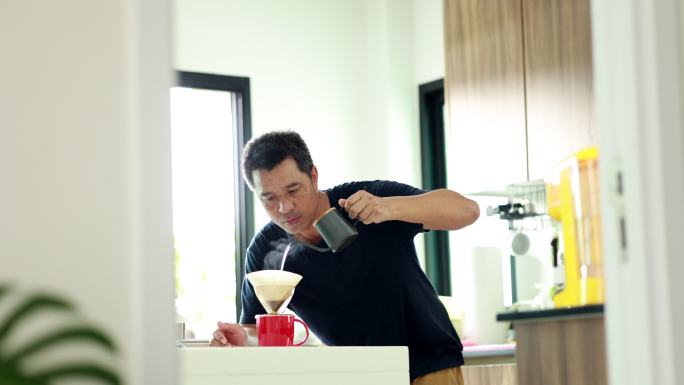 亚洲男人在厨房里滴咖啡