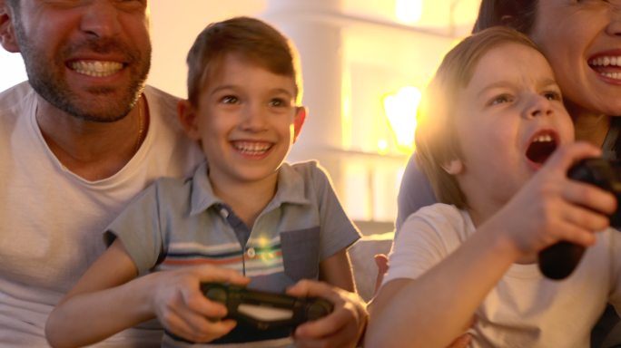 快乐的家庭在家玩电子游戏时玩得很开心。