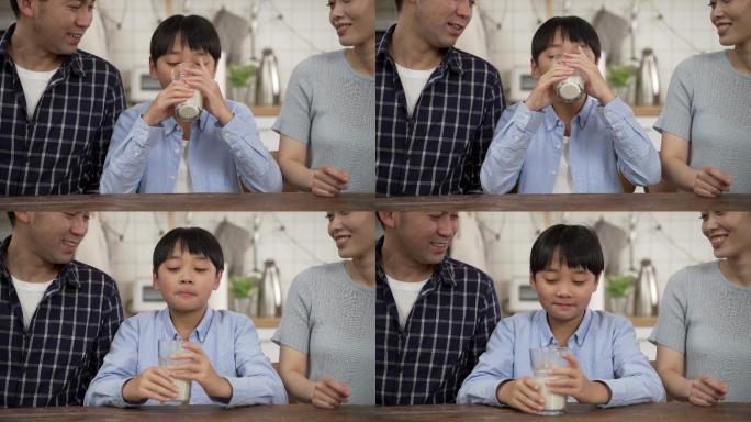 快乐的亚洲家庭在厨房里玩得很开心。亚洲爸爸妈妈和小儿子在一起，小男孩在桌上抱着并喝着牛奶