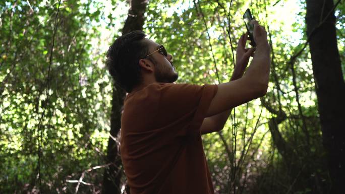 这个年轻人正在树林里寻找一个蜂窝网络。