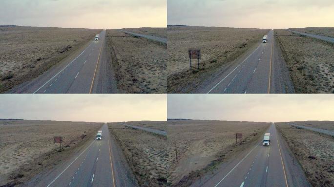 犹他州沙漠黄昏时分，无人驾驶飞机拍摄了一辆半卡车，车上的灯亮着