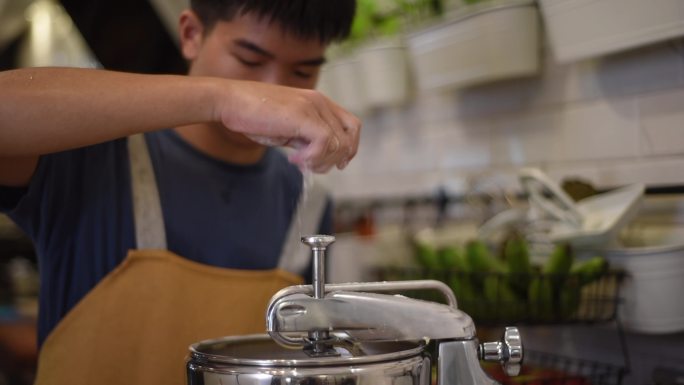 亚洲华人面包师少年男孩在厨房的立式搅拌机中添加面粉