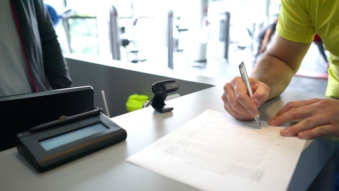 无法辨认的客户在健身房入口处签署表格