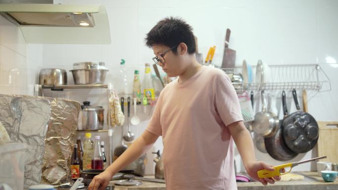 亚洲学龄前男孩在家里的厨房里用煤气灯打开燃烧器，这是一种生活方式的概念。